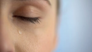 Face of unhappy woman crying, closeup eye with teardrops, dry eye example, lack of tears