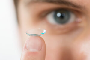 Close-up Of Young Man Holding Contact Lens On Finger