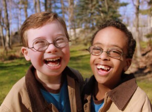 Two male children laughing one child has Down Syndrome (special needs)