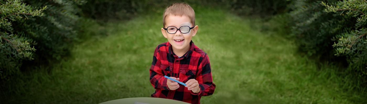 Child with eye patch outdoors, representing vision therapy for pediatric patients